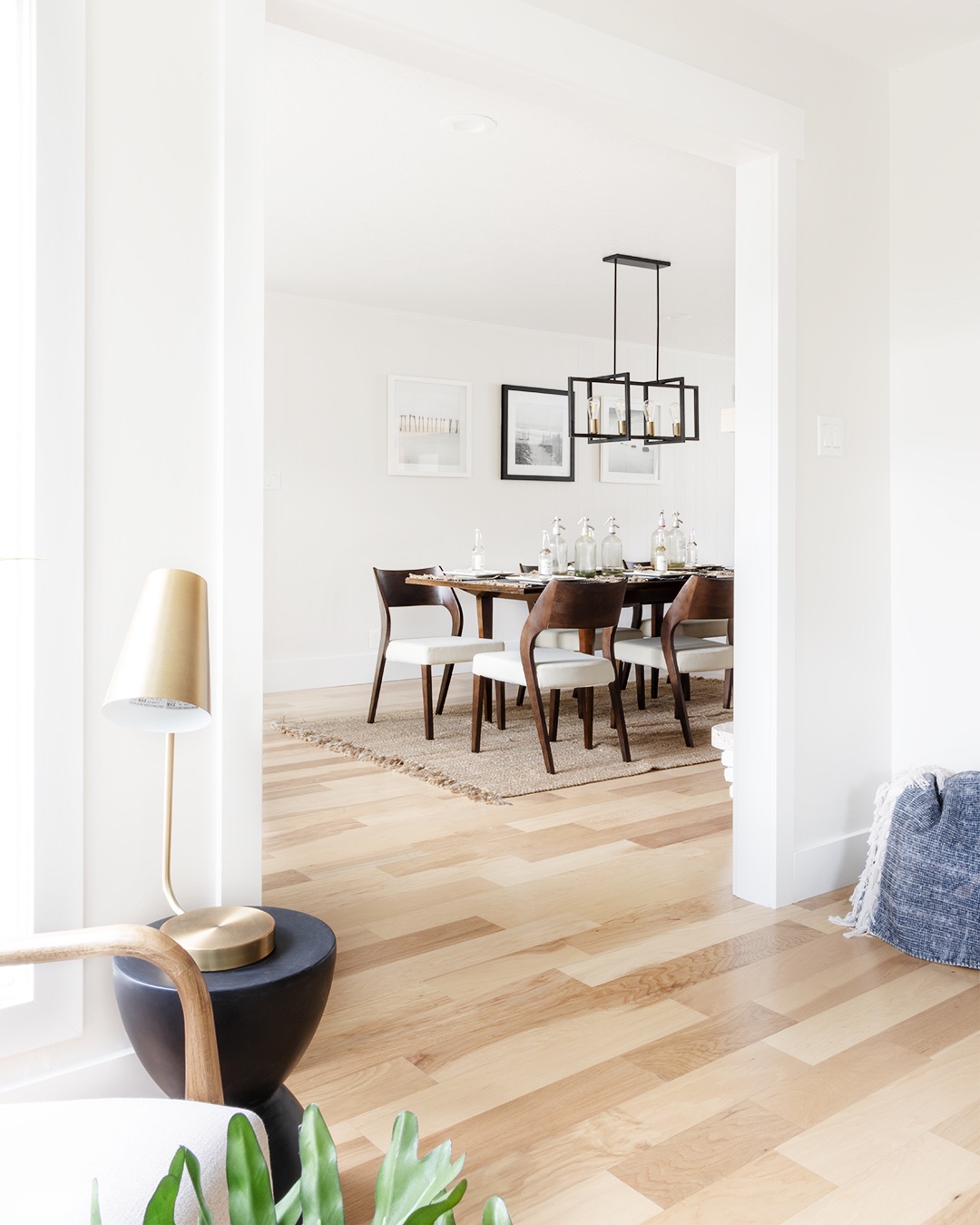 White living room with wooden floors and table, minimalist design with natural light.