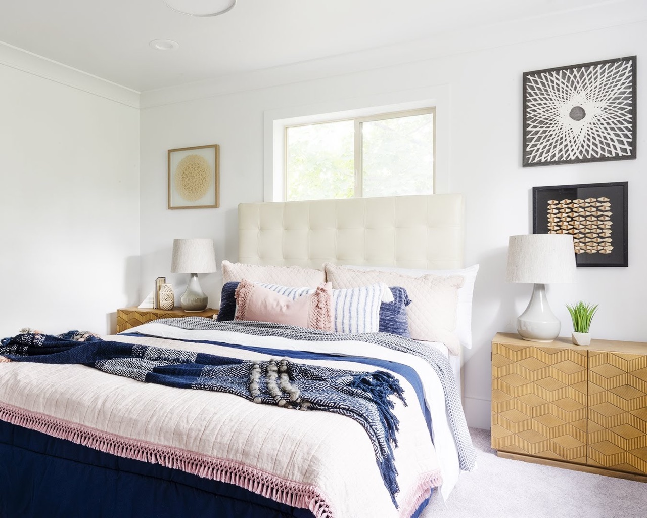 Bedroom with white bed, blue and pink bedspread, and white headboard.