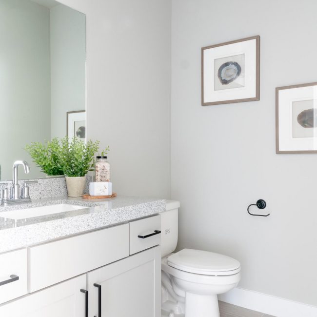 A pristine bathroom featuring white cabinets and a toilet.