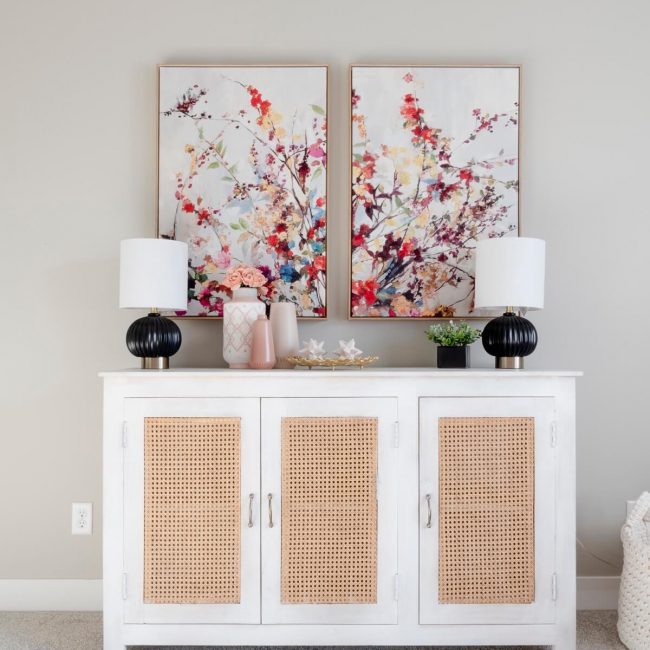 A white sideboard with two paintings on it, adding elegance and artistic touch to the room's decor.