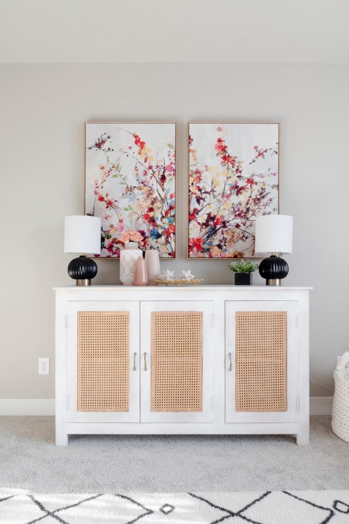 A white sideboard with two paintings on it, adding elegance and artistic touch to the room's decor.