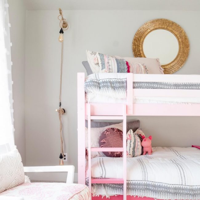 Pink bunk bed with white rug and pink chair in bedroom.