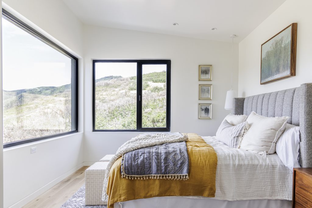 A bedroom with a bed, window, wooden nightstand, and cabinet.