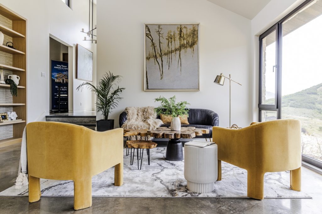 A living room with yellow chairs, a large painting, and a sofa.