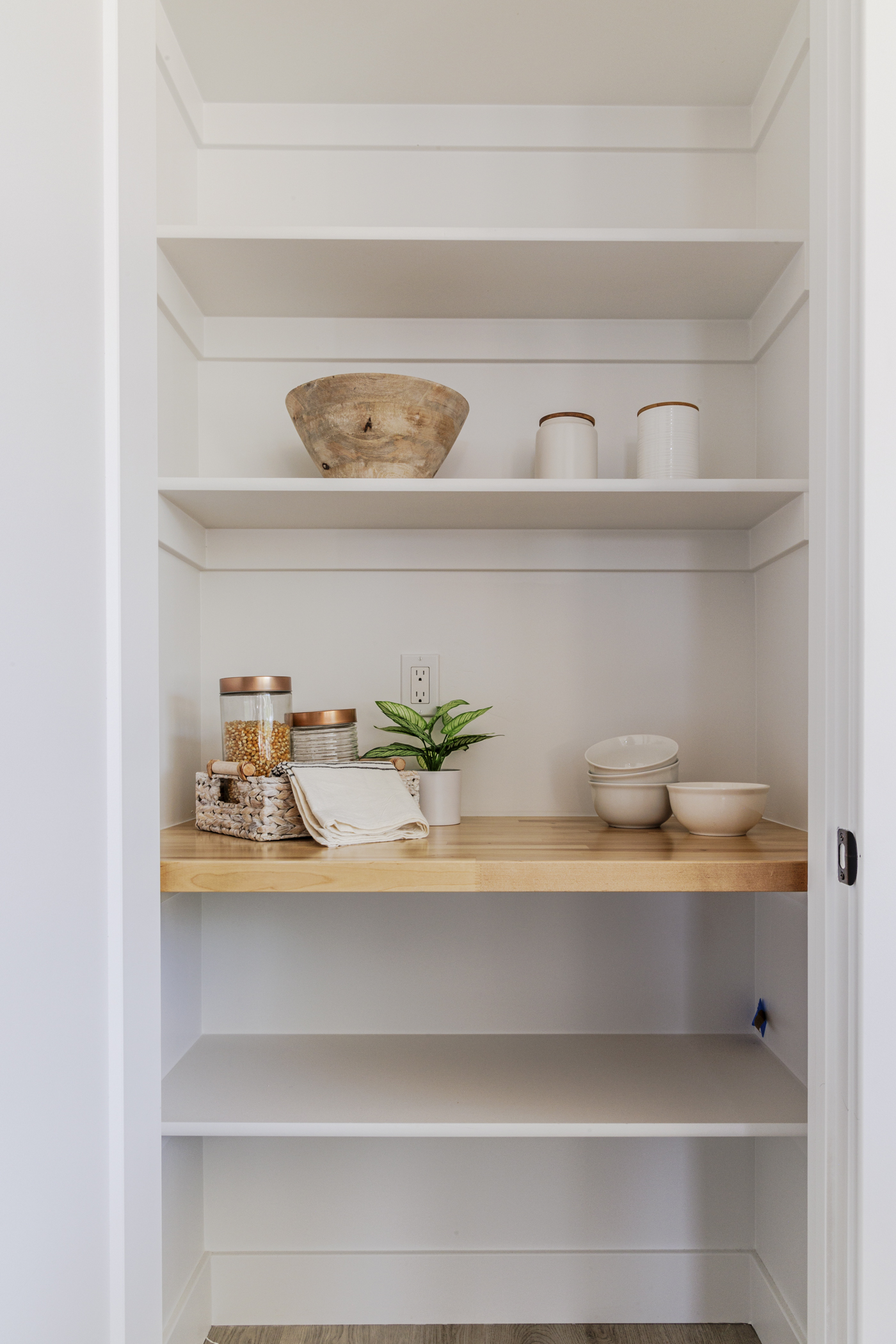 White pantry cabinet with shelves and a wooden shelf inside.