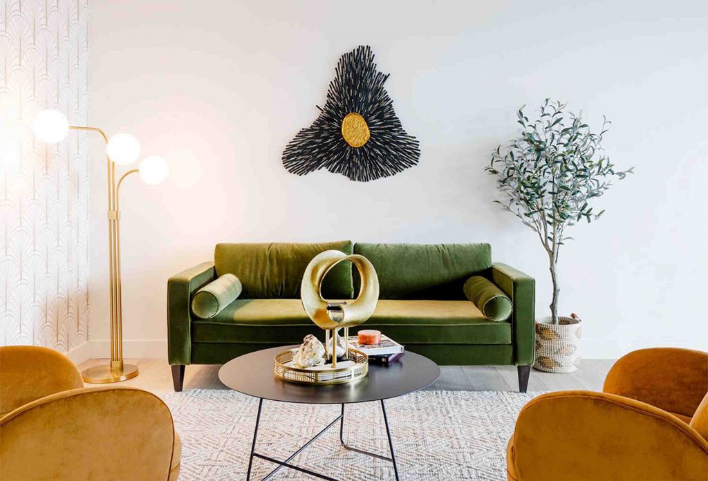 A luxurious living room with green velvet sofas, gold accents, and a gold coffee table.