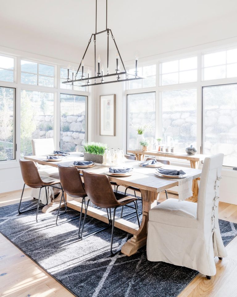 A spacious dining room with a large wooden table surrounded by chairs.