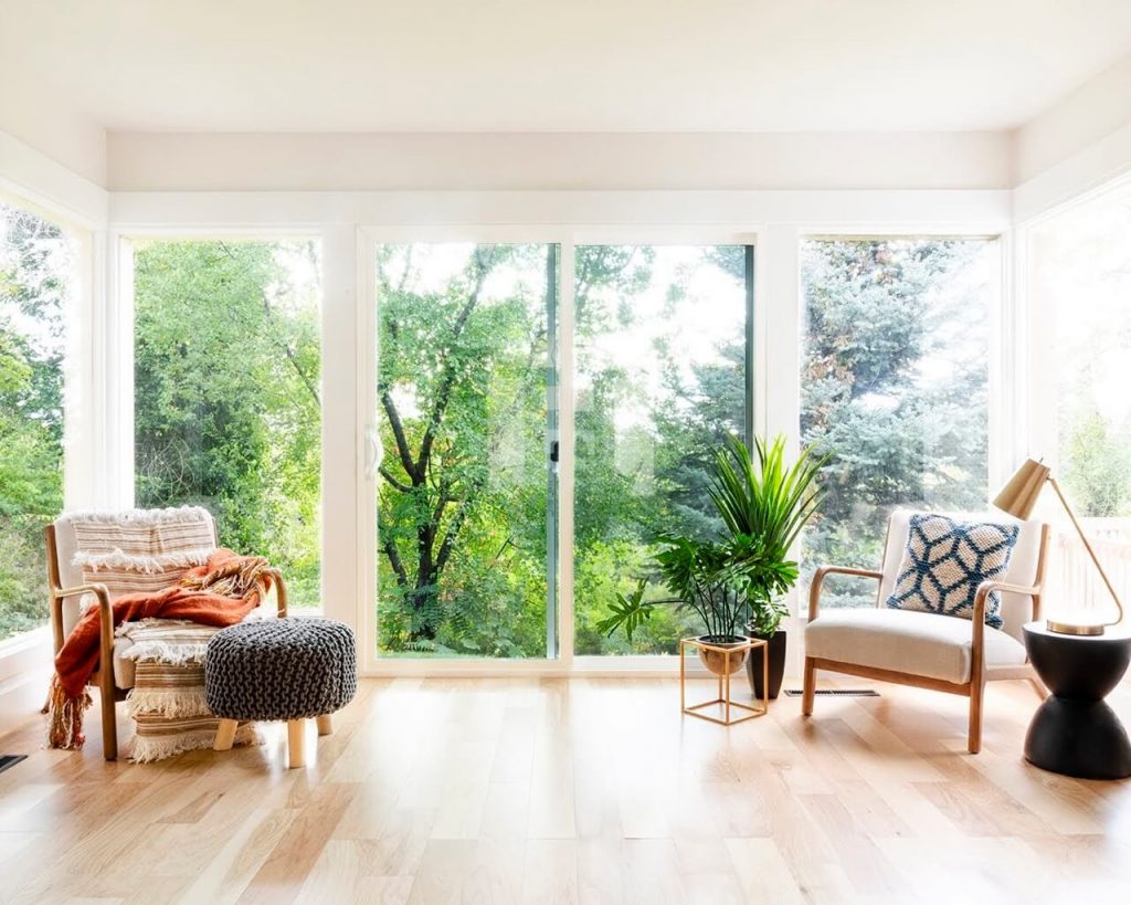 Spacious living room with large windows, wood floors, and a sofa.