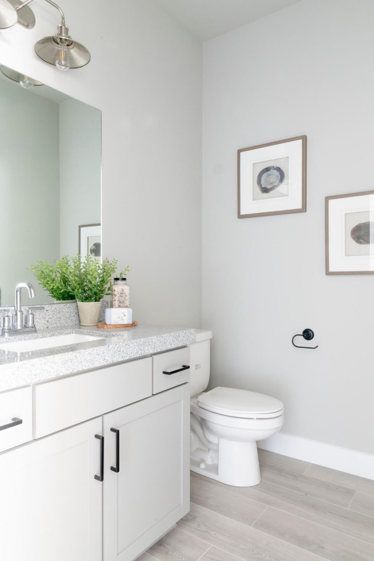 A pristine bathroom featuring white cabinets and a toilet.