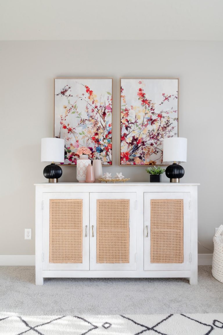 A white sideboard with two paintings on it, adding elegance and artistic touch to the room's decor.